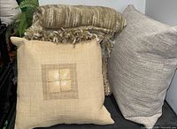 Three toss cushions and striped knit throw blanket grouped together