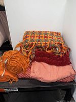 Stack of six throws on shelf showing colours and textures