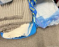 Gray and white coverlet atop blue bag with other bedding