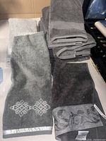 Loose grey towels with decorative borders and stack of plain grey towels