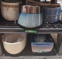 Group of assorted ceramic planters on shelf