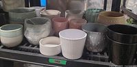 Shelf with assorted ceramic and clay pots in varied colours and finishes