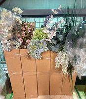 Cardboard box containing multiple artificial floral stems of various types and colors