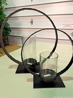 Two bronze ring hurricane candle holders on table