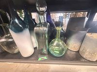 Multiple blue and green glass bottles, decanter with stopper, pillar candle
