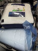 Two packaged duvet inserts on top of bin