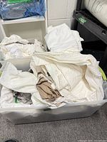 Large tote filled with folded white and beige bed skirts
