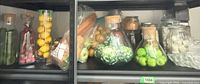 Overall shelf view showing multiple glass containers with faux produce and dry goods