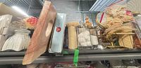 Shelf view showing multiple bath décor items including wood tray edge, ceramic canister, glass jars, loofah, soap dish