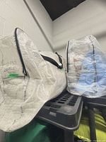 Two zippered white storage bags containing bedding sets, lot reference numbers visible