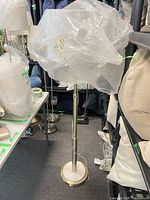 Full view of brass and marble floor lamp with shade wrapped in plastic