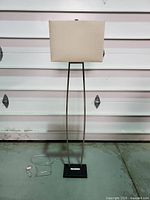 Full view of brushed nickel and black floor lamp with linen shade