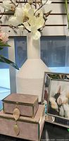 Vase, faux magnolia branches, suede boxes, silver frame grouped together