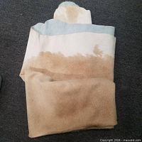 Folded light brown cowhide rug on grey floor