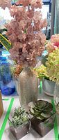 Large silver vase with pink faux hydrangea beside two glass succulent cubes
