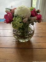 Front view of floral arrangement in glass vase on wood table