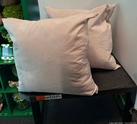 Two light blush pillows on table