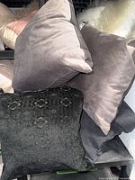 Stack of grey and black decorative pillows showing variety of fabrics