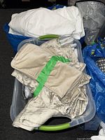 Tub containing folded beige pleated shams and packaged white sham