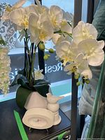 Faux orchid arrangement, clock and bird grouped
