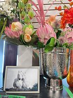 Group shot showing silver hammered vase with arrangement, partial view of white and beige vases