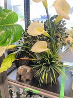 Shelf view showing two black vases with faux floral arrangements and stone elephant