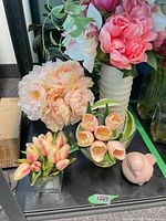 All items grouped on shelf: three glass vases with different faux flowers, tall white vase with mixed flowers, pink bird figurine