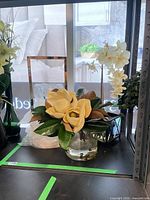 Magnolia arrangement, orchid arrangement, lantern together on shelf