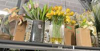 Shelf view showing multiple artificial floral arrangements in various vases