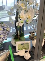 Faux orchid arrangement, frame and bird figurines grouped
