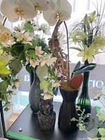 All three vases with floral arrangements and wolf statue grouped on shelf