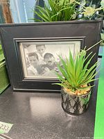 Black photo frame with faux succulent in metal pot
