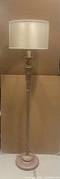 Full view of bronze-tone fluted column floor lamp with cream drum shade
