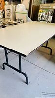 Side view of folding table showing laminate top and black metal legs