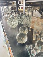 Shelf with multiple faceted glass spheres, bubble glass balls, crystal candlesticks and glass pillars.