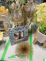 Group showing mercury glass orbs, ornate frame, starburst, gold vase with faux leaves