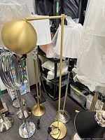 Full view of gold/brass adjustable floor lamp among other lamps