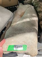 Folded light brown hide rug showing hair-on surface and sticker 1492