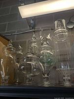 Multiple clear glass apothecary jars with lids on shelf