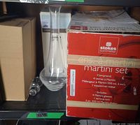 Shelf view with Stokes martini set box, glass decanter, stopper, plain box