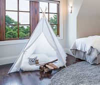 Marketing image showing assembled white teepee tent set up in bedroom
