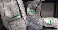 Three clear storage bags containing packaged white bedding items on shelf