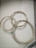 Full view of three overlapping gold metal rings wall sculpture mounted on white wall
