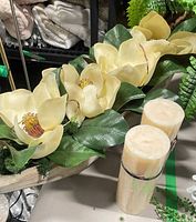 Centerpiece close-up with magnolia blooms, leaves, moss and two pillar candles