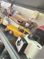 Shelf view showing yellow taxi, Polaroid camera, typewriter, helmet, shaker, decorative car