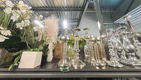 shelf view of faux florals and multiple silver candlesticks