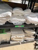 Stacks of folded white textured shower curtains and pillowcases on shelving