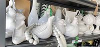 Shelf of white ceramic frog, birds, vases, bead garland