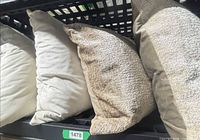 Four neutral cushions on storage rack, two light grey microfiber and two textured taupe