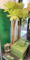 Overall lot showing faux florals in vases, green orb on box, silver-tone clock